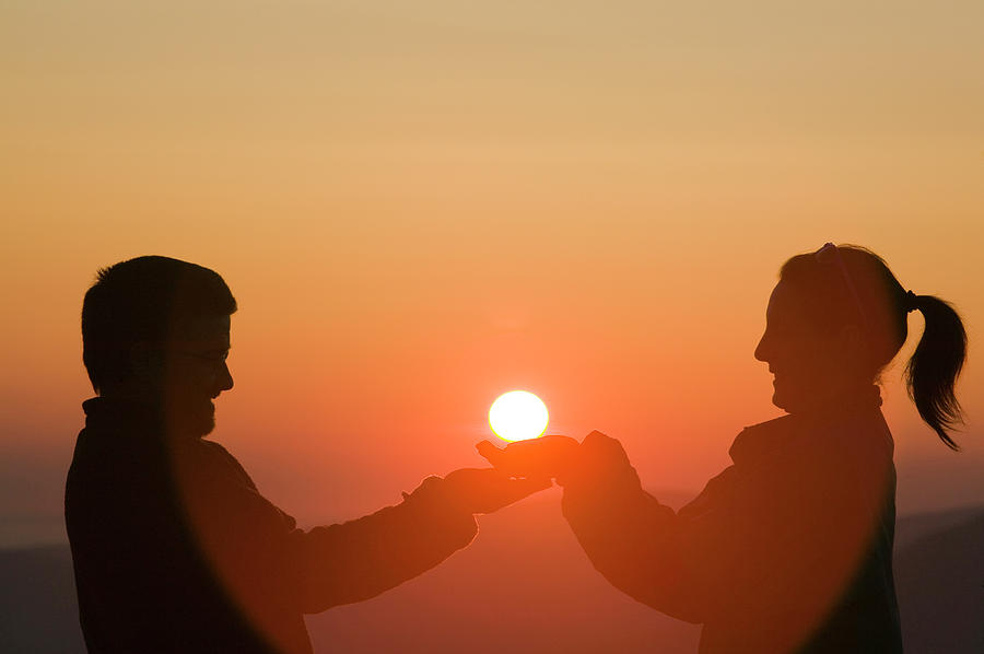 a man and a woman holding the sun in their hands